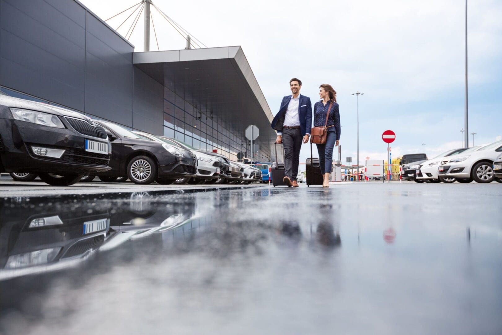 Couple walking near parked cars outside building.